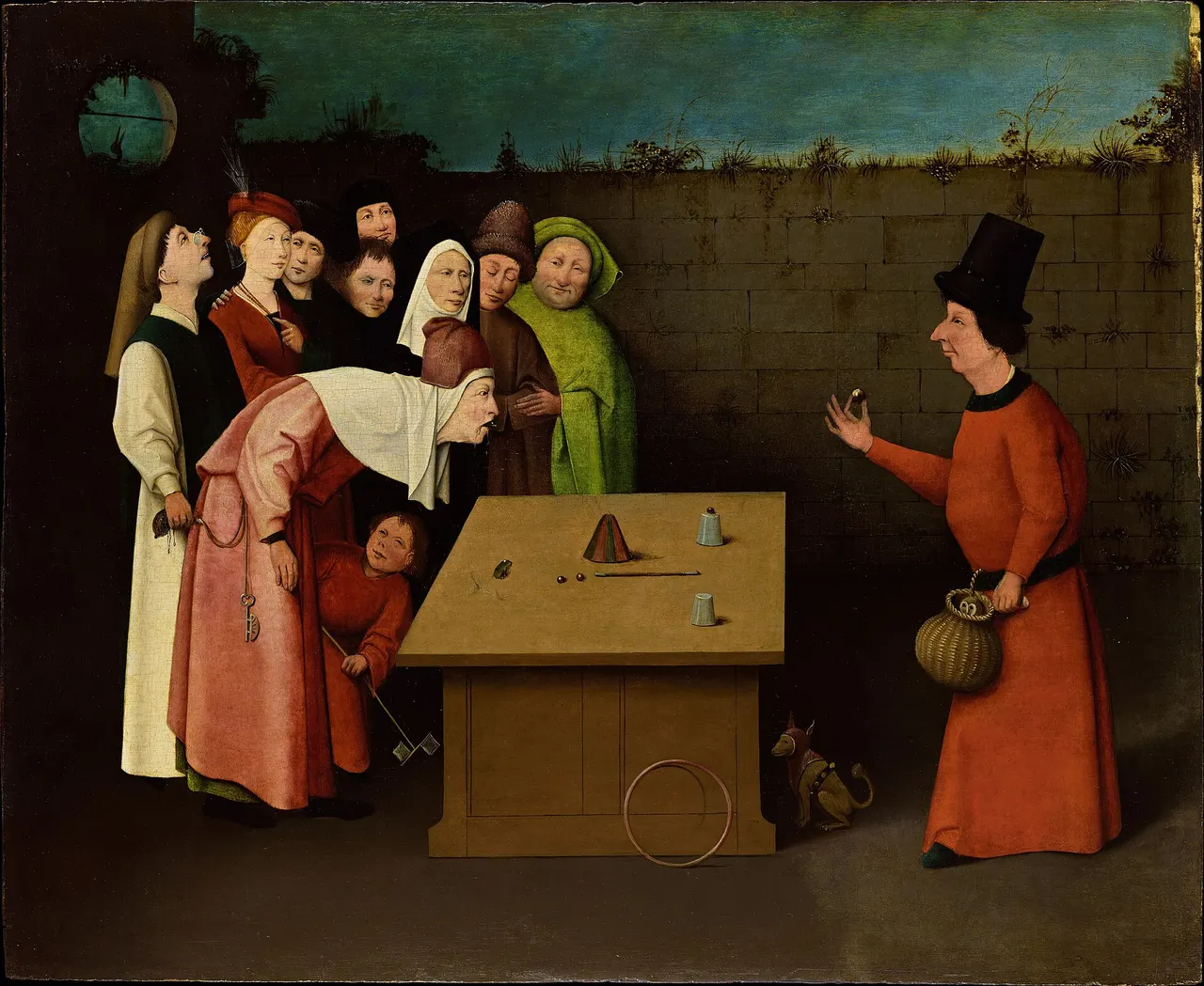 A street magician in a red robe and a tall black hat holds up a small ball in front of a table with cups on it. A crowd stares. A man in pink bends over the table with his mouth open, while a man behind him quietly takes his purse.